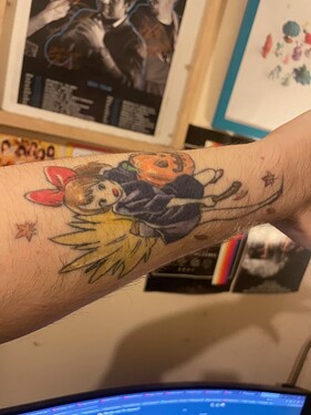 Tattoo of Kiki from Kiki's Delivery Service on a broom and holding a Jack-O-Lantern in Autumn